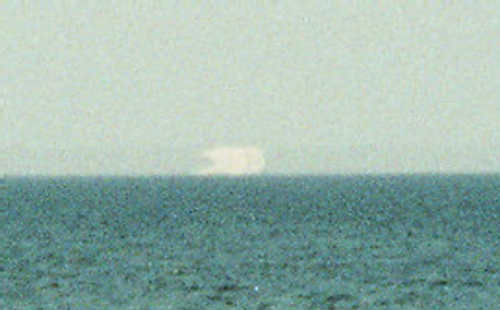 Foto: ein Schiff, über dem aufgrund einer Luftspiegelung sein umgekehrtes Spiegelbild zu sehen ist